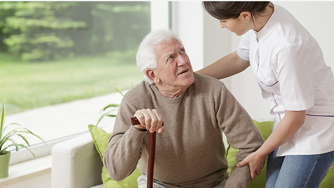 A BetterWay carer warmly helping a gentleman to his feet at home