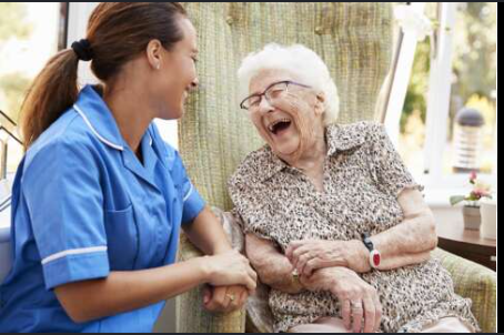 Carer and older woman laughing together